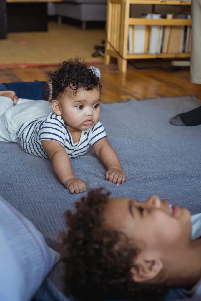 Two cute babies enjoying playtime indoors with joyful expressions.