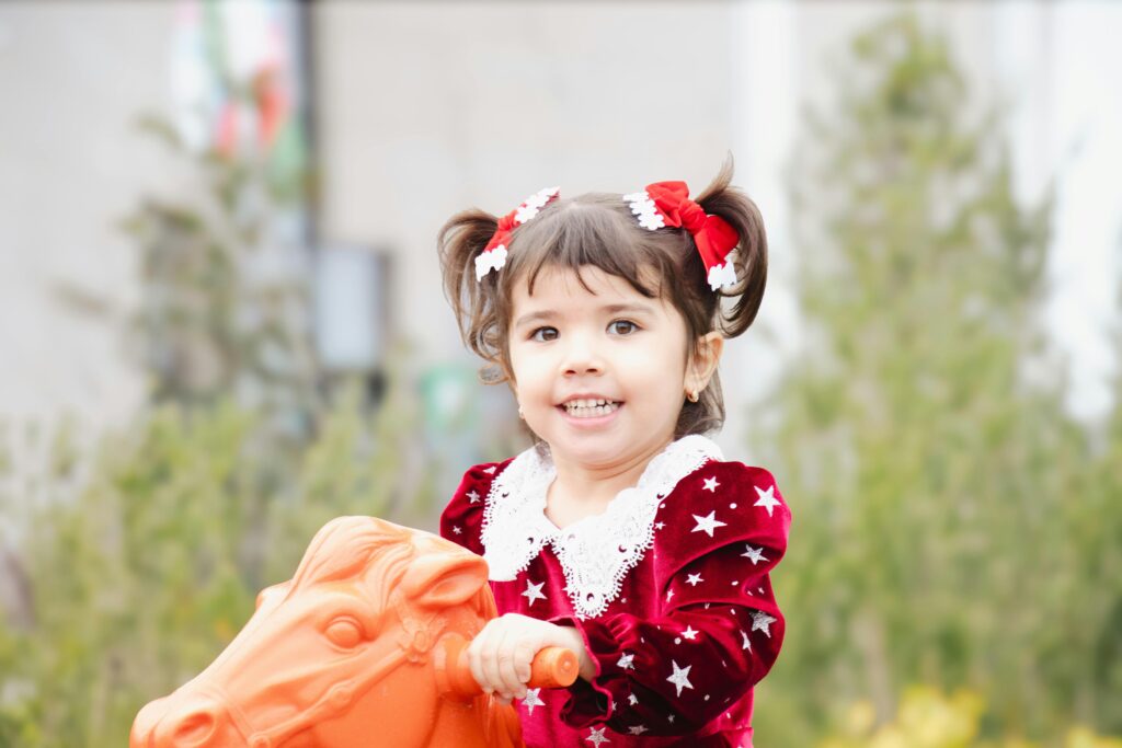 A young girl enjoying a playful ride outside in Salyan, showcasing joy and innocence.