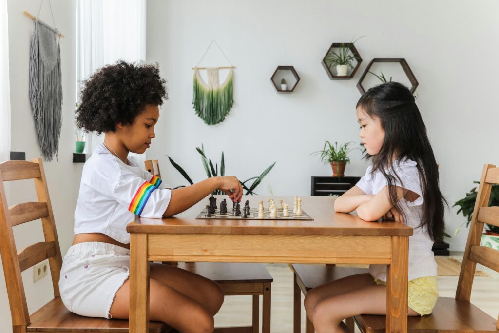 Two diverse children playing chess, focusing intently in a cozy, modern room.