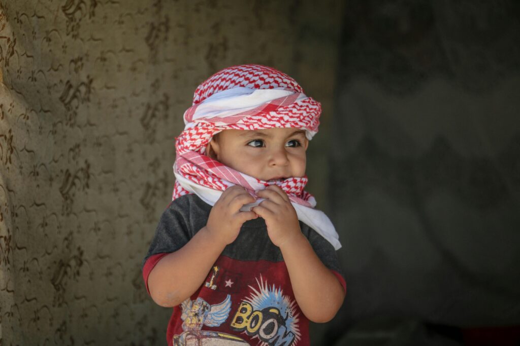 Middle Eastern child wearing traditional keffiyeh, captured outdoors in Syria.